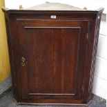 A George III oak splay front wall mounted corner cabinet, outswept cornice, dentil frieze,