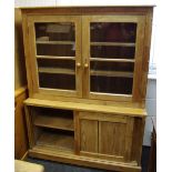 A stripped pine kitchen cabinet, two glazed doors enclosing shelving to top, projecting base,