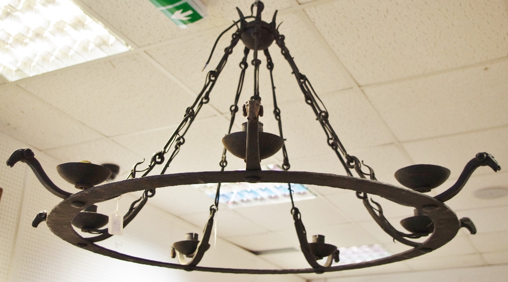 A wrought iron seven light chandelier with stylised ram head terminals