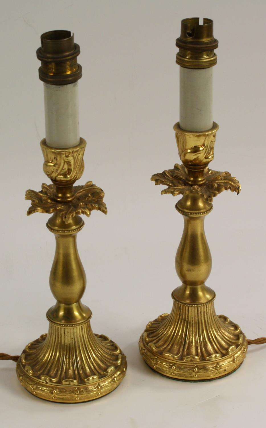 A pair of early 20th century gilt metal table lamps, the candlesticks cast and chased with acanthus,