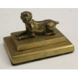 A post-Regency gilt-patinated bronze desk weight, naturalistically cast as a recumbent dog,