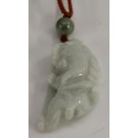 A Chinese pale celadon jade pendant, carved as a temple lion,