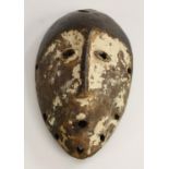 Tribal Art - an African mask, of eliptical outline, stylised features with pronounced central ridge,