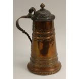 A large 19th century beaten copper tankard, hinged domed cover with bud finial, scroll handle,