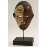 Tribal Art - an Igbo spirit mask, eliptical eyes, bared teeth, decorated in red and white pigment,