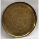 A large Indo-Persian brass circular charger, the field chased in the Islamic taste with script,