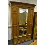 An Edwardian pine wardrobe, outswept cornice, central mirrored door, deep drawer to base,