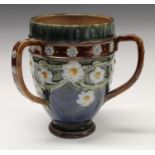 A Doulton Lambeth stoneware three handled tyg, tube lined with a band of white and blue flowers,