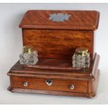 An early 20th century oak desk top standish, lidded letter rack back, twin inkwell pen tray,