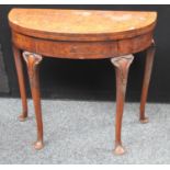 A Queen Anne style walnut demilune card table, folding top enclosing a baize lined playing surface,