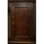 A George III oak wall hanging corner cupboard,