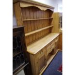 A country kitchen pine dresser, outswept cornice, shaped frieze and shelving to top,