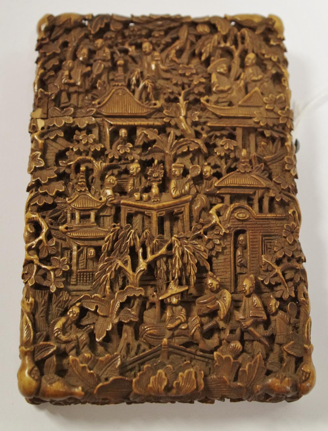 An oriental card case carved with domestic scenes.