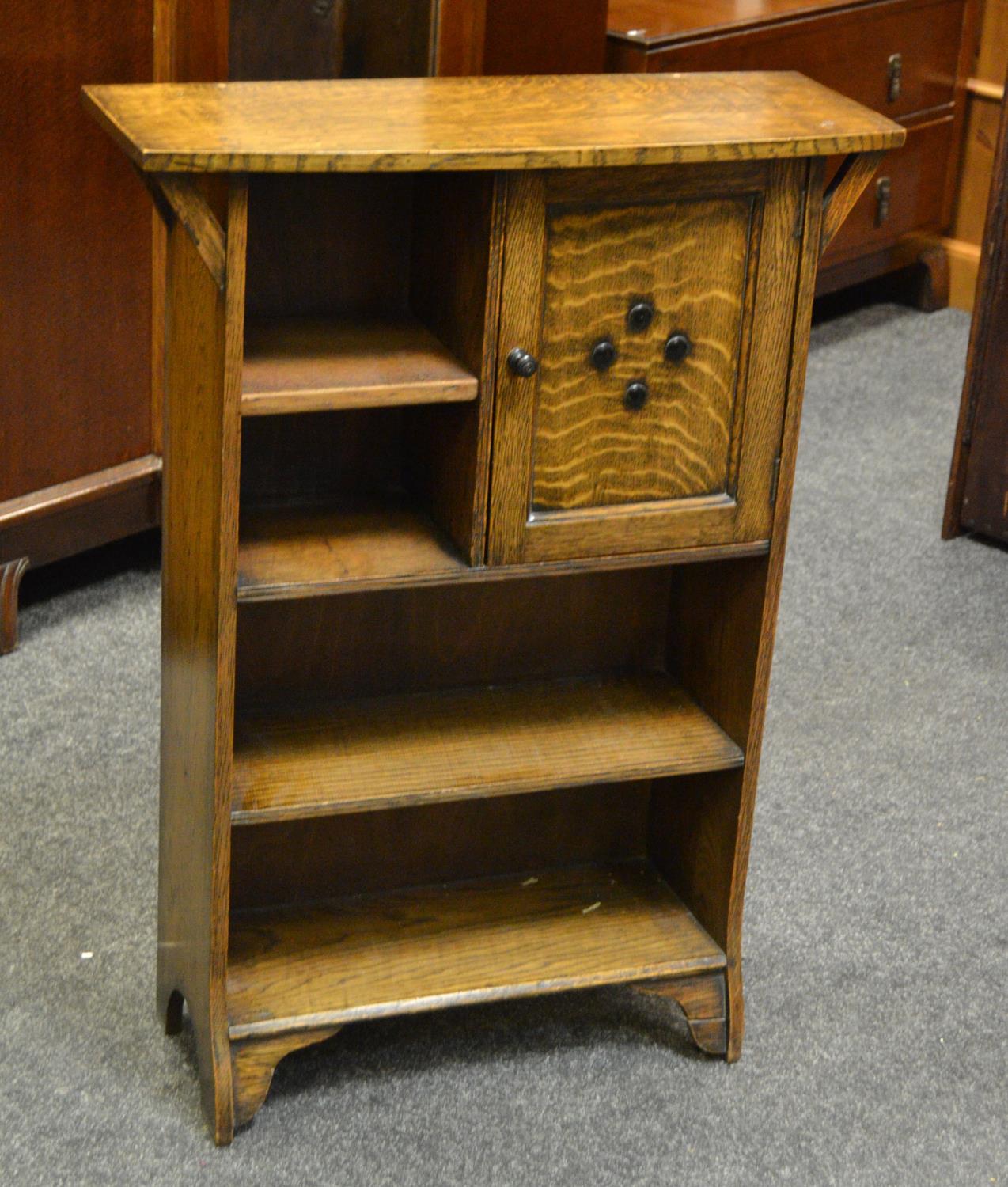 An Arts and Crafts oak bookcase cabinet, bowed top over an arrangement of cupboard and shelving.