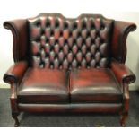 A sang de boeuf two seater high winged back Chesterfield sofa 143 W x 108 H x 85cm D