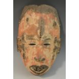 Tribal Art - an Igbo mask, scarified features and bared teeth,