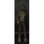 Tribal Art - an African figure, standing on elongated legs, wearing a bold tooth necklace,