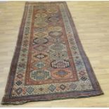 A Middle Eastern rectangular woollen carpet, the runner with a field of twenty-four geometric guls,