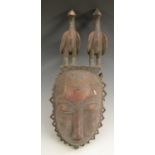 Tribal Art - a Baule mask, crested by a pair of birds, shaped border, 41cm long,
