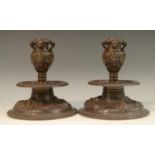 A pair of Renaissance Revival brown patinated bronze capstan candlesticks, boldly cast with masks,