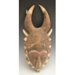 Tribal Art - a Baule mask, crested by horns and decorated in tones of white, red and blue,