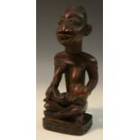 Tribal Art - a Yoruba maternity figure, seated, cross-legged, nursing her infant, 17.