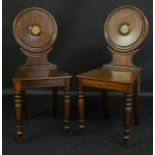 A pair of early Victorian mahogany armorial hall chairs,