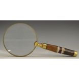A brass connossieur's hand lens, the circular magnifying glass with banded haft,