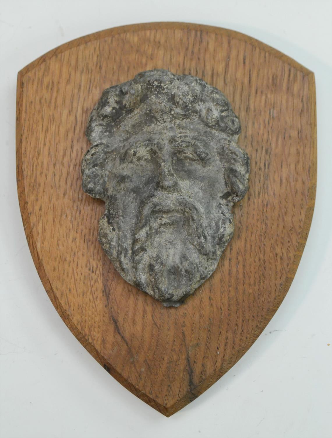 A 17th/18th century lead boss, cast as a bearded mask, mounted for the connoisseur on an oak shield,