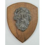 A 17th/18th century lead boss, cast as a bearded mask, mounted for the connoisseur on an oak shield,