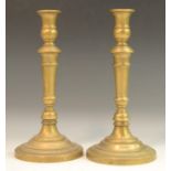 A pair of French Empire brass candlesticks, campana sconces, knopped stems,