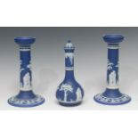 A pair of Wedgwood Jasperware candlesticks, typically sprigged in white with classical figures,