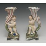A pair of Staffordshire figural spill vases, of cherubs holding cornucopias,