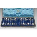 A set of twelve silver coffee spoons, bows ensuite, each with entwined branch and scroll hafts,