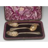 A pair of Victorian silver gilt berry spoons, the bowls embossed with fruit and foliage,
