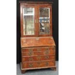 A George I/early George II walnut bureau cabinet, moulded cornice above a pair of mirrored doors,