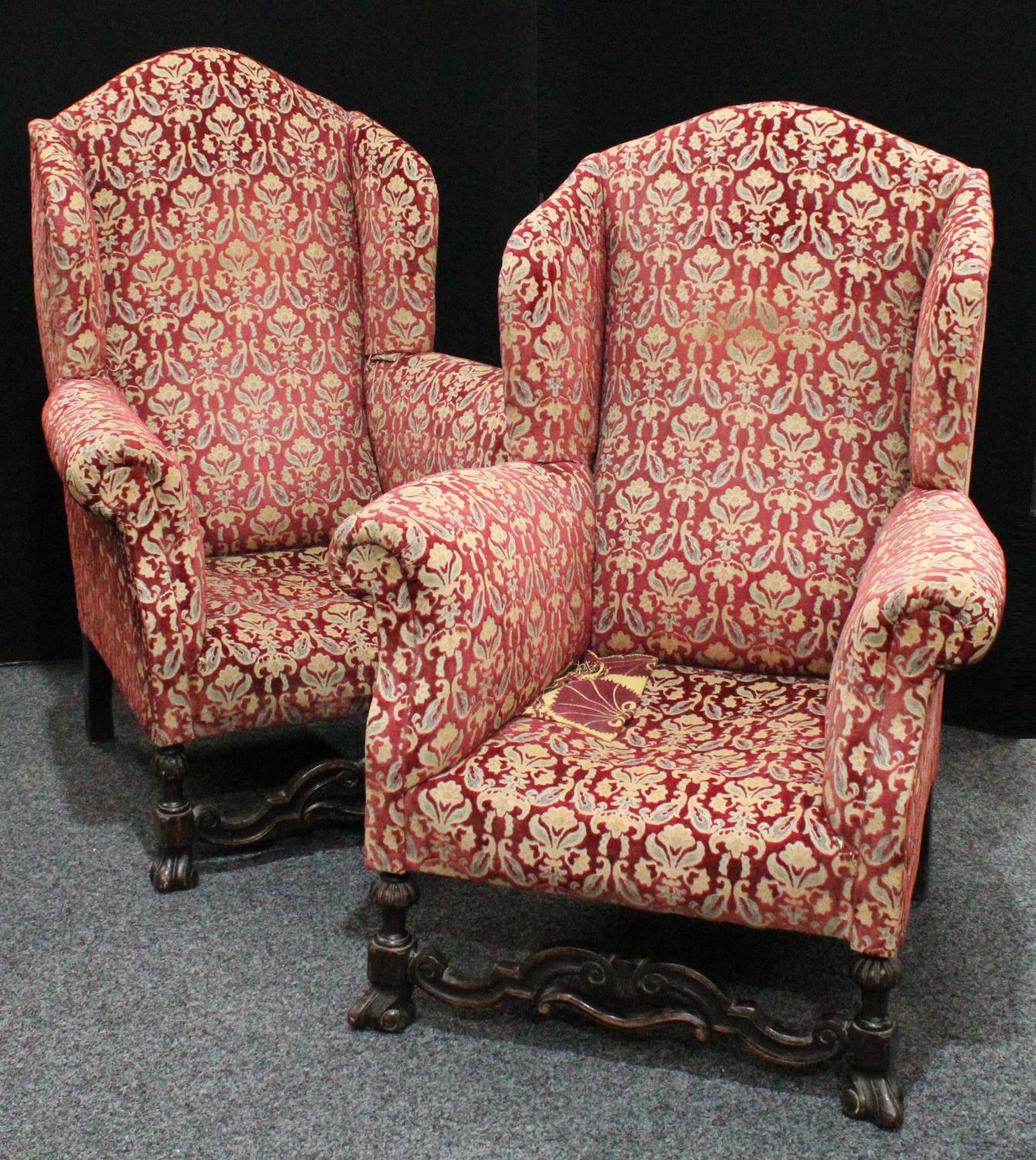 A pair of substantial George II style wing armchairs, of Spanish Baroque influence,