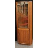 A contemporary Ercol corner display cabinet, glazed door enclosing two glass shelves,