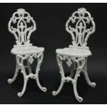 A pair of 19th century heavy cast iron garden chairs, of small and neat proportions,