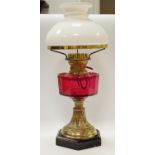 A Victorian oil lamp, opaque shade, cranberry reservoir, brass base,