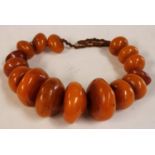 A graduated single strand amber coloured resinous bead necklace,