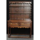 A George III style oak dresser, shallow outswept cornice above a shaped apron and two plate racks,