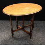 An oak folding coaching type occasional table, oval top, bobbin turned supports, 61cm high (open),