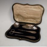 A George V silver mounted lady's manicure set, nail buffer, files, pot and cover, steel scissors,