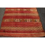 A Middle Eastern hand knotted carpet, in tones of mustard, black and white on a red ground,