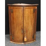 A George III oak bow front corner cupboard,