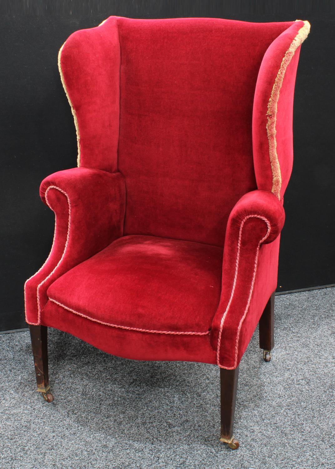 An early 20th century wingback armchair, scroll arms, stuffed over upholstery, 118.