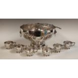 An EPNS punch bowl, embossed with foliate scrolls, two lion mask handles, ladle, six cups,