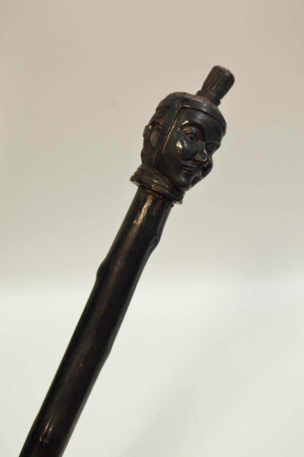 An unusual walking stick the pommel in the form of a Chinese immortal mask mounted on a japanned