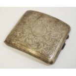 An early 20th century silver cigarette case chased with scrolling foliage with vacant circular